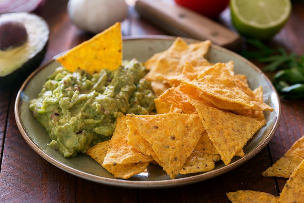 Foto plaat van guacamole met tortillachips en ingrediënten