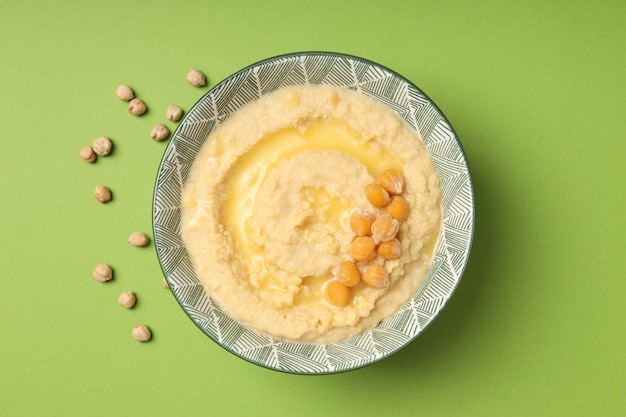 Plaat van hummus op groene achtergrond bovenaanzicht