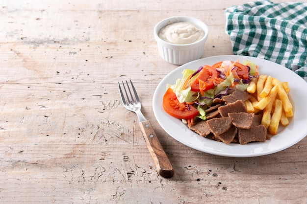 Plaat van kebab, groenten en frietjes op houten tafel