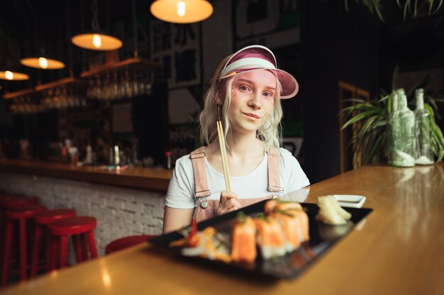 Plaat van sushi rolt in restaurant met eetstokjes van de vrouwenholding