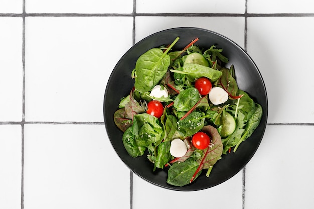 Plaat van verse groene salade tegel achtergrond Mix van salade bladeren met komkommer tomaten mozzarella