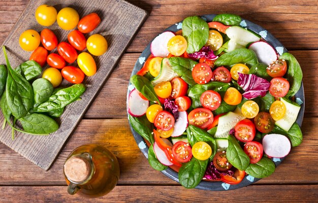 Plaat van verse salade op houten tafel, bovenaanzicht