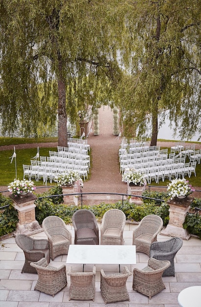 Plaats voor huwelijksceremonie met huwelijksboog versierd met bloemen en witte stoelen aan elke kant van de boog buitenshuis. Voorbereiding voor huwelijksceremonie buiten in de buurt van meer.