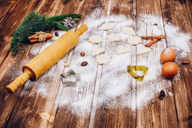 Place on the wooden table with rolling pin, dough, eggs and flour for cooking Christmas pastry