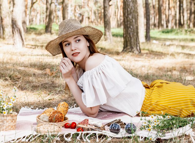 plaid on which lies a picnic food, sausages, nuts, red tomatoes and fresh buns. 