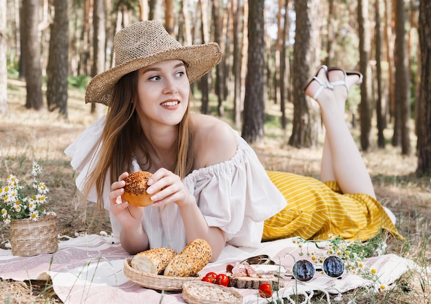 Photo plaid on which lies a picnic food, sausages, nuts, red tomatoes and fresh buns.