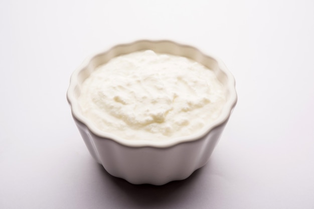 Plain curd or yogurt or Dahi in Hindi, served in a bowl over moody background. Selective focus