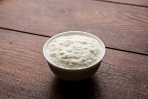 Plain curd or yogurt or Dahi in Hindi, served in a bowl over moody background. Selective focus