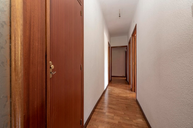 Plain white painted corridor with entrance to various rooms fitted wardrobes and oak parquet floor