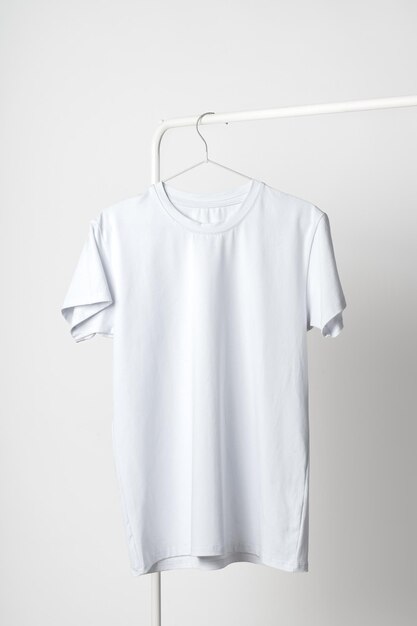 Plain white tshirt hanging on hanger against white wall