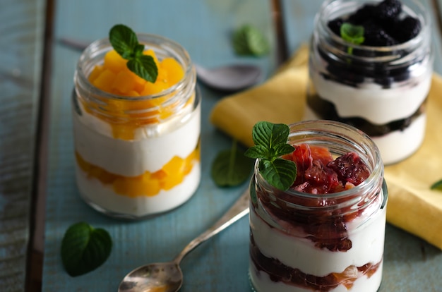 Plain yoghurt in jars with blood oranges pieces of peach and blackberries