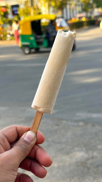 Plak ijs Kulfi in de nazomer op de weg in de hand