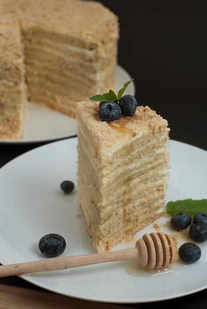 Plak van gelaagde zelfgemaakte honingcake met bosbes.