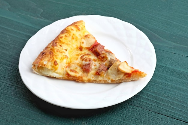 Plak van pizza met vlees topping geserveerd op witte plaat geselecteerde focus close-up