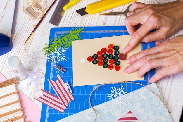 Plakboek achtergrond. Meisje maakt kerstkaart en gereedschap met decoratie