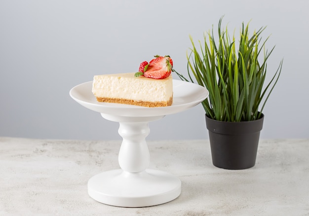 Foto plakje aardbei cheesecake op een witte plaat op een taart staan op een witte achtergrond.