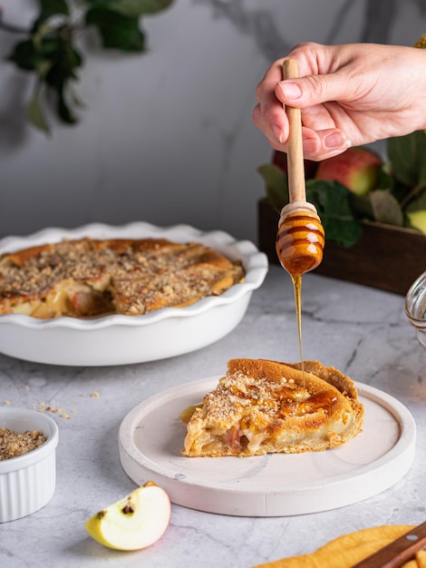 Plakje appeltaart op de witte plaat met honing