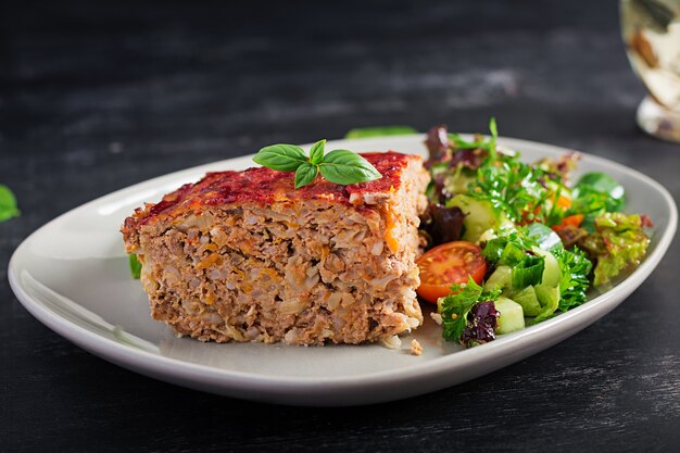 Plakje braadpan met rijst, rundergehakt en kool met tomatensaus erop versierd met basilicum op het bord