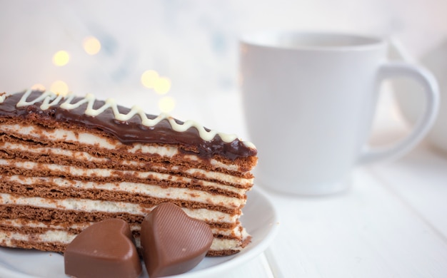 Plakje cake op een schotel en harten op een witte achtergrond