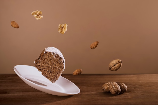 Foto plakje chocoladebiscuit met poedersuiker vliegt naast noten en amandelen