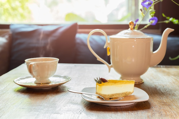 Plakje citroen cheesecake met kopje thee met bloemen.