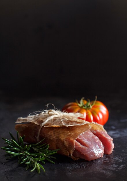 Plakje rauwe kalkoen steak met rozemarijn en tomaten op donkere tafel close-up