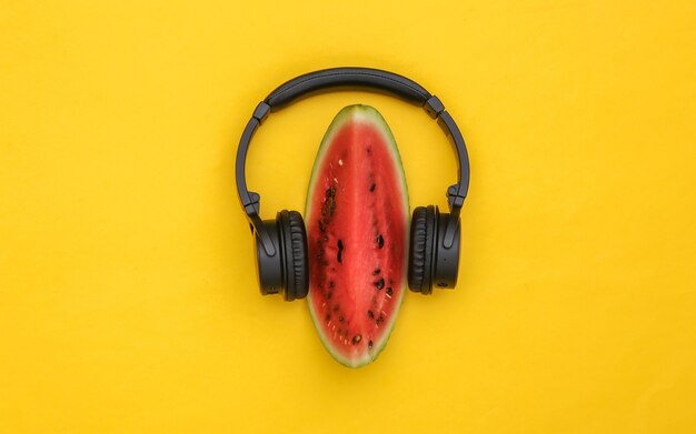 Plakje rijpe watermeloen en stereo koptelefoon op gele achtergrond. Zomerplezier. Bovenaanzicht. plat leggen