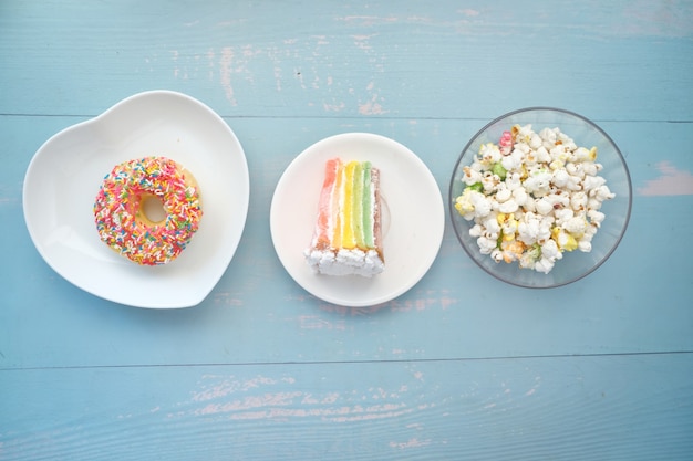 Plakje slagroomtaart donuts en popcorn op tafel