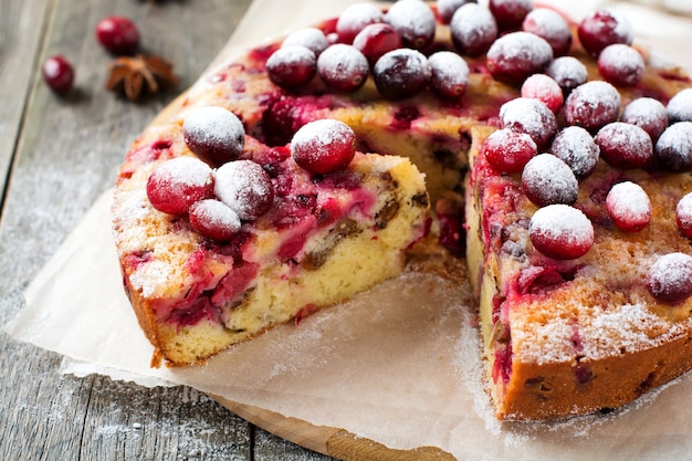 Plakje zelfgemaakte cranberrycake met walnoten, bessen en poedersuiker op de oude houten fone