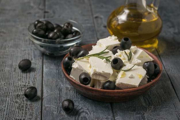 Plakjes fetakaas, zwarte olijven en olijfolie op een houten tafel. Natuurlijke kaas gemaakt van schapenmelk.