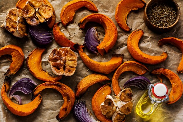 Plakjes gebakken pompoen, uien, knoflook, kruiden en plakjes kaas Dorblu op bakpapier en oude blauwe steen