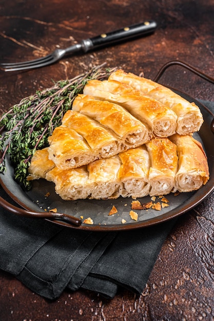 Plakjes gebakken ronde Borek kaastaart in keukenblad met kruiden Donkere achtergrond Bovenaanzicht
