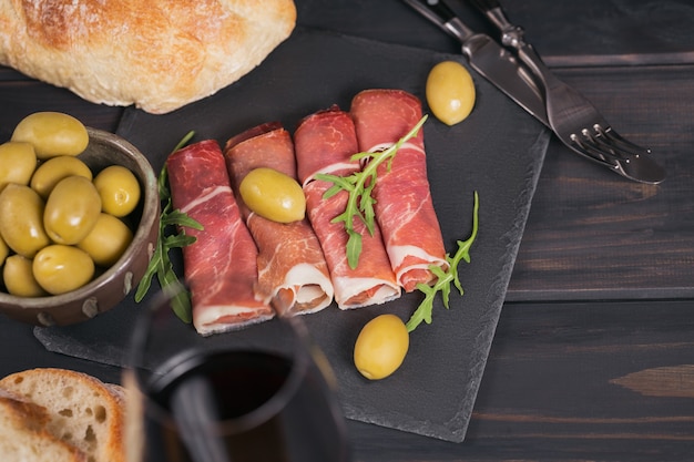 plakjes gerookte ham of spaanse jamon serrano of italiaanse prosciutto crudo met glas rode wijn