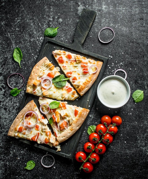 Plakjes pizza met tomaten en kaassaus in kom