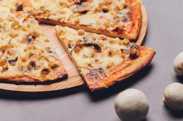Plakjes pizza op rustieke houten dienblad en donkere achtergrond.