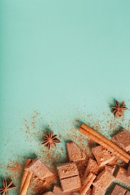 Plakjes pure chocolade met kaneel en kruiden op een pastelgroene ondergrond