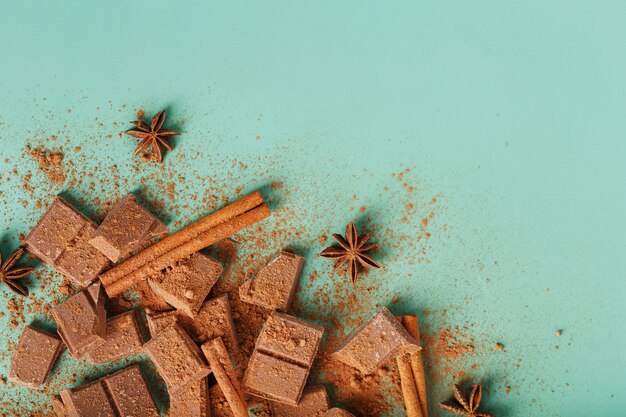 Plakjes pure chocolade met kaneel en kruiden op een pastelgroene ondergrond