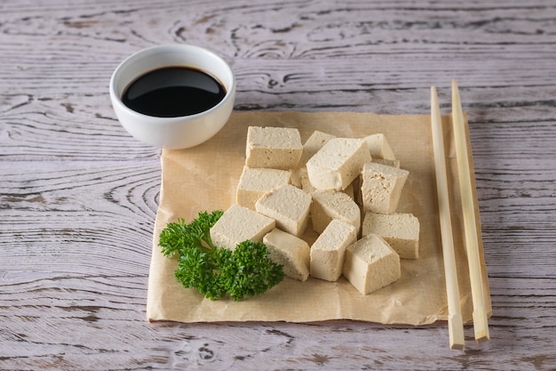 Plakjes tofu kaas, sojasaus en houten stokjes. Soja kaas. Vegetarisch product.