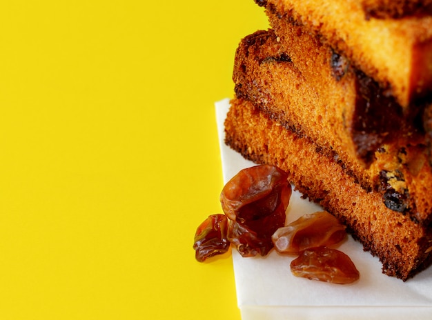 Foto plakjes traditionele gedroogde vruchten cake voor kerst klaar om te eten met wat rozijnen op geel