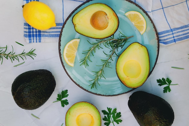 Plakjes verse avocado met kruiden en citroenen liggen op tafel op een blauw bord. Plat leggen. Bovenaanzicht