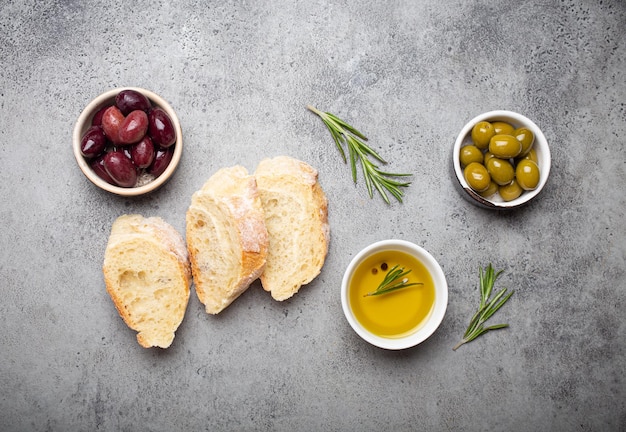 Plakjes verse ciabatta groene en bruine olijven olijfolie