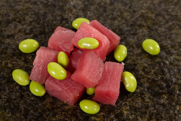 Plakjes verse tonijn met edamame bonen op een houten tafel