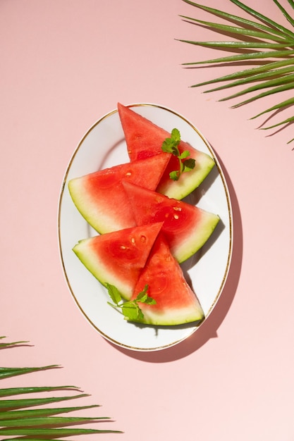 Plakjes verse watermeloen in een bord bovenaanzicht roze achtergrond Zomervoedsel