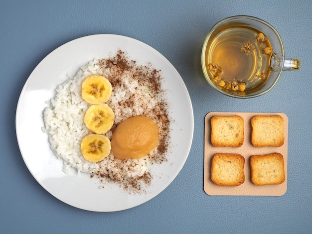 Plakjes witte rijst, banaan, appelmoes, toast en kamillethee Lunch van het BRAT-dieetmaaltijdplan