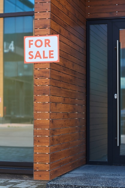 Plakkaat te koop opknoping op de muur van modern huis