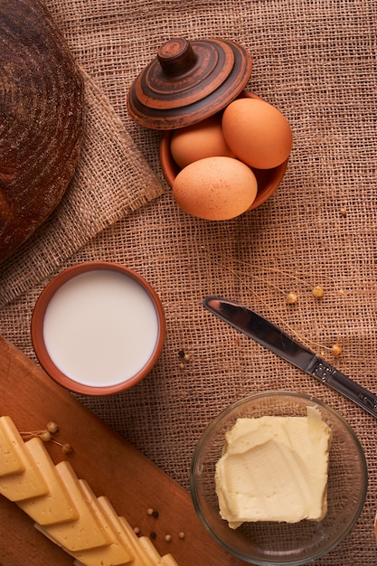 Plakken van kaas op houten bureau dichtbij baguette en melk