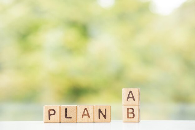 Plan a of b woord is geschreven op houten kubussen op een groene zomerachtergrond Close-up van houten elementen