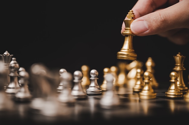 Запланируйте ведущую стратегию успешной концепции лидера деловой конкуренции, шахматная доска «рука игрока», кладущая золотую пешку