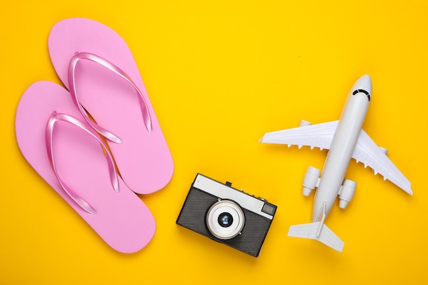 Plane figurine, flip flops, camera on a yellow.