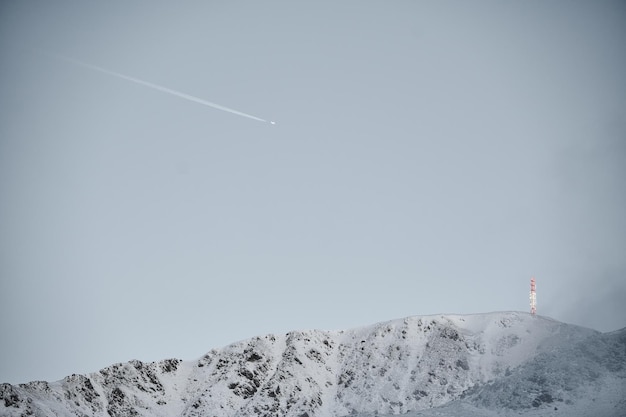 スキー場近くの雪に覆われた山脈の上を飛ぶ飛行機